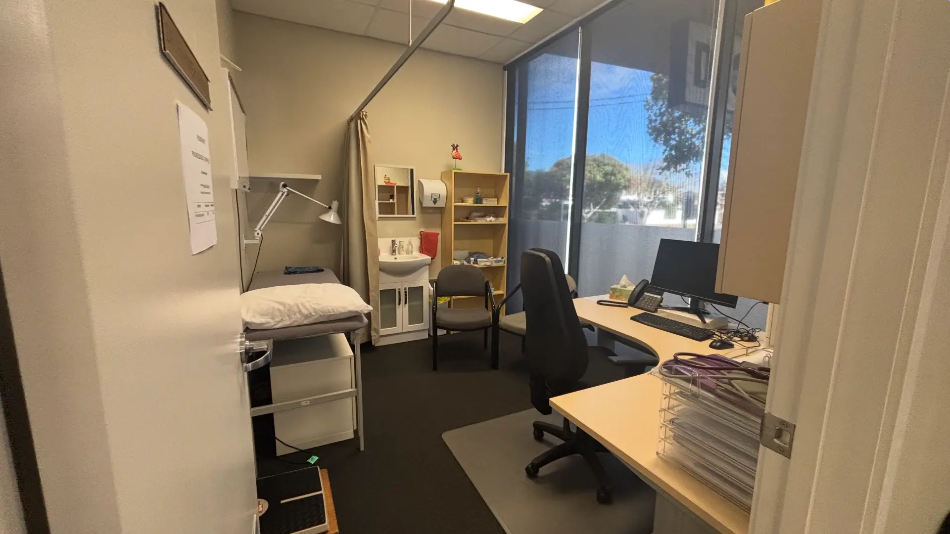 The consulting room with examination bed, sink and desk seen from the entrance